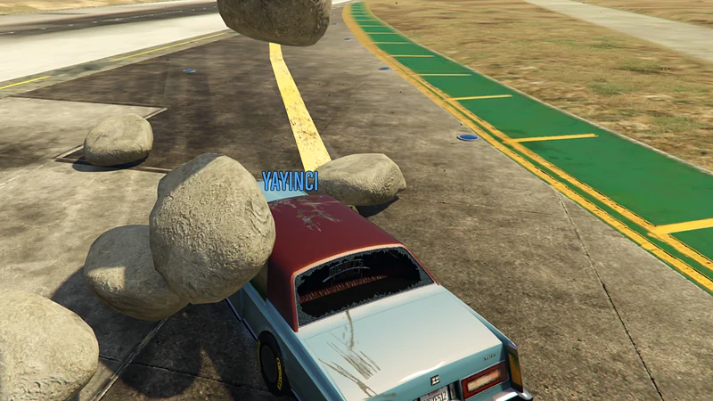 GTA V oyun içi: Arabanın üstüne iri kayalar düşmüş, arka cam kırık.